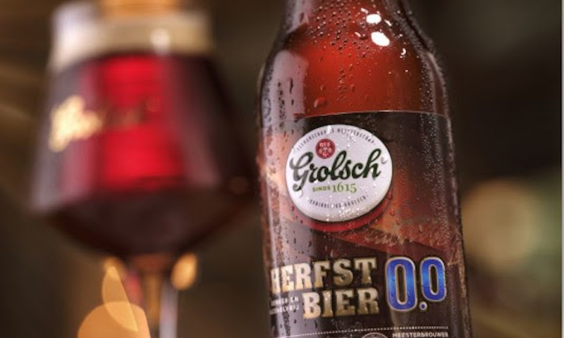 Grolsch Herfstbier 0.0% flesje op de voorgrond en gevuld proeverij glas op de achtergrond
